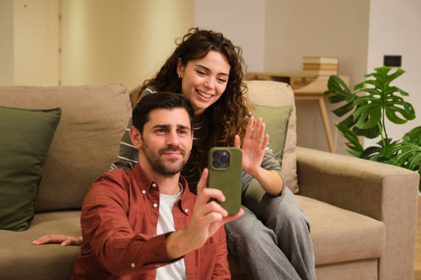 istock Happy couple video calling with friends using smartphone at home 2175493747