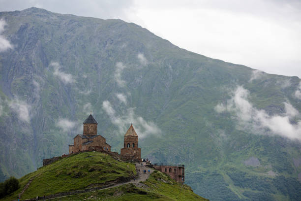 A breathtaking view of a mountain range with a ancient Gergeti Trinity Church, under Mount Kazbek near the village of Stepantsminda in Georgia