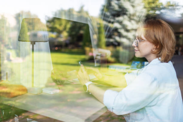 istock Mid adult woman working from home using computer and mobile 2175502762