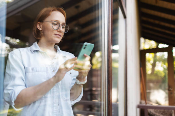 istock Mid adult woman using mobile, portrait through the window 2175502906