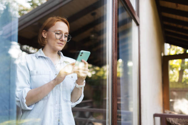 istock Mid adult woman using mobile, portrait through the window 2175502966