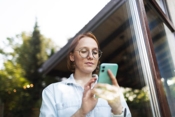 istock Mid adult woman using mobile, portrait through the window 2175503103
