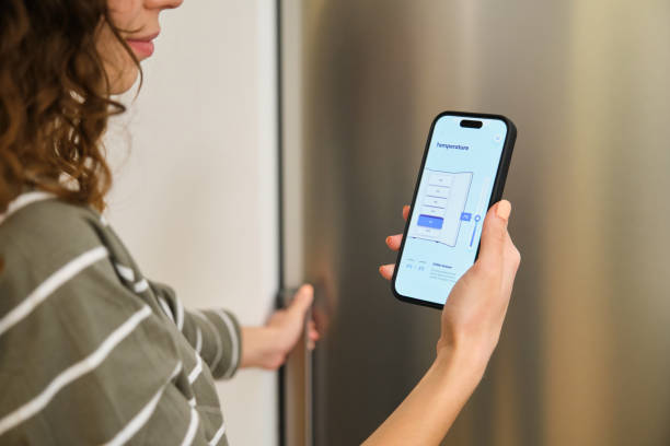 istock Woman using smartphone app controlling smart refrigerator temperature at home 2175503272