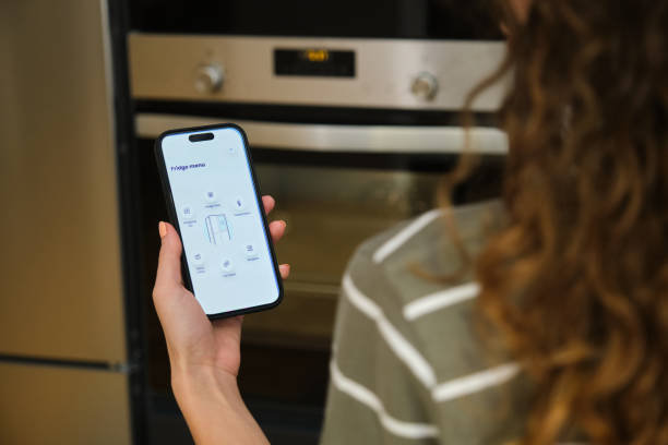 istock Woman using smartphone app controlling smart refrigerator from home 2175503357