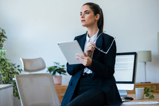 istock Beauty business woman using her digital tablet while sitting on a desk in a modern startup office 2175504478