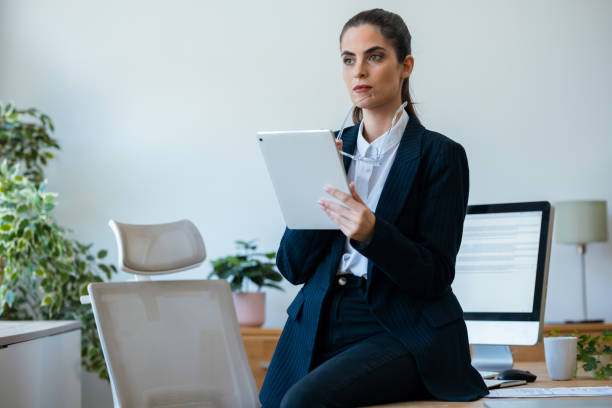 istock Beauty business woman using her digital tablet while sitting on a desk in a modern startup office 2175504484