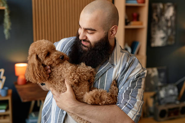 istock Smiling Man Cuddling Fluffy Brown Dog at Home 2175516442