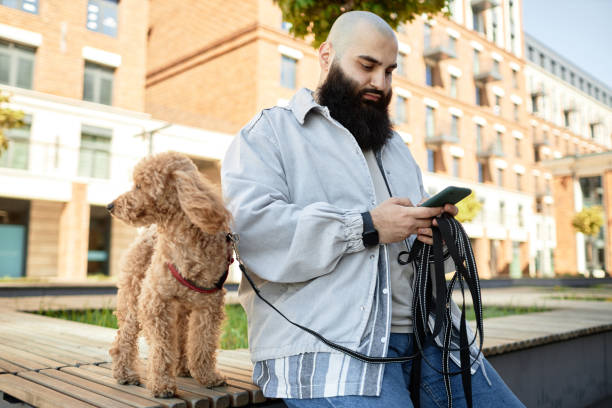 istock Bearded Man Walking Dog and Checking Smartphone 2175516464