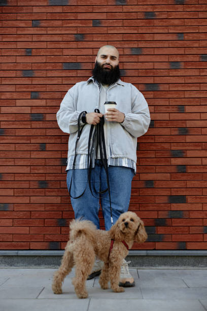 istock Holding Coffee Cup While Walking Dog in Urban Area 2175516476