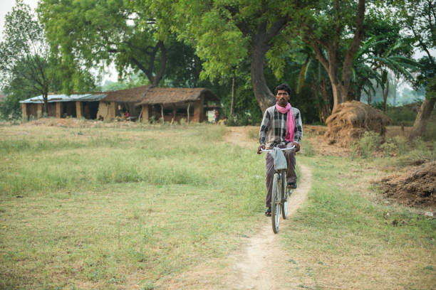 Raebareli, Uttar Pradesh, India-June 16, 2015: A man rides his bicycle on a village path in Raebareli.