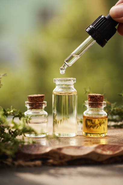 Drop of aromatherapy essential oil falling from a pipette into a bottle outdoors in nature