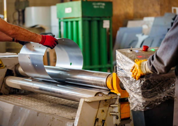 istock depicts a worker handling a flat sheet of metal as it is fed into a rolling machine 2175527934