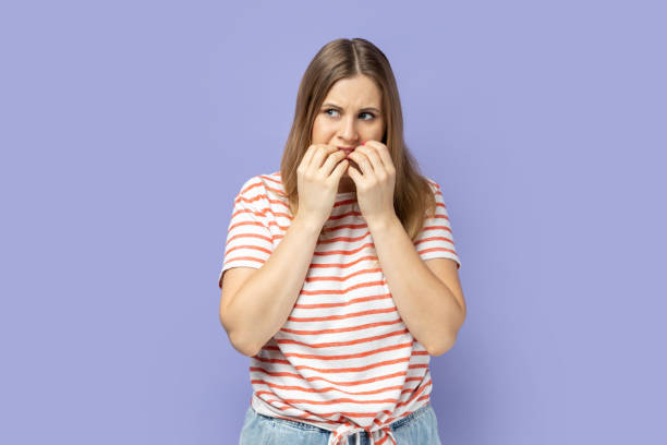 istock Woman standing looking away and biting her finger nails, having problems. 2175531269