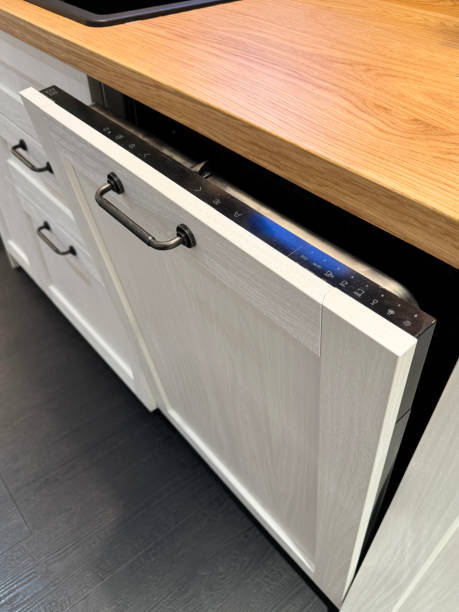 istock Close-up image of integrated dishwasher, door ajar displaying control panel with wash cycle and options selection, wood grain effect kitchen counter, focus on foreground 2175532590