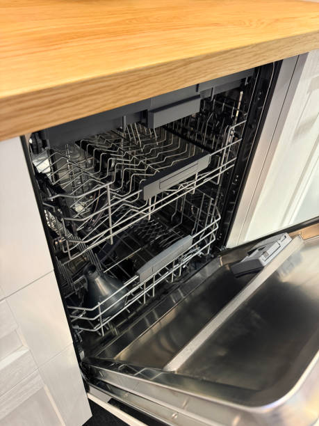 istock Image of integrated dishwasher interior, plastic upper and lower spray arm, filter, soap funnel on lower rack, wood grain effect kitchen counter, focus on foreground 2175532601