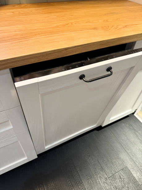 istock Image of integrated dishwasher, door ajar displaying control panel with wash cycle and options selection, wood grain effect kitchen counter, wood laminated flooring, focus on foreground 2175532617
