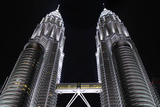 The Petronas Towers in Kuala Lumpur (Malaysia), the tallest twin towers in the world, shot at night, with a deep contrast between the skyscrapers light and the dark sky that makes a color photo looking like a black and white one.