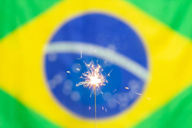 A sparkler shines brightly with the Brazilian flag in the background, ccelebrating Brazilian Flag Day with a festive vibe on November 19th.