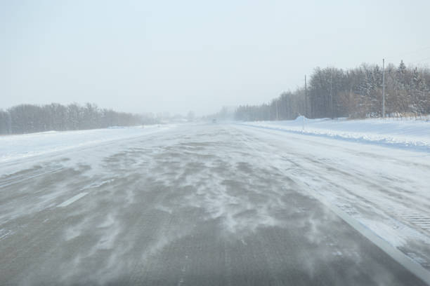 Wind blowing snow across the highway in winter creating limited visability.
