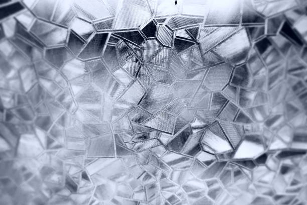 Embossed glass background. Corrugated glass monochrome. Refraction of light in a bumpy transparent surface under backlight. The play of white and gray highlights. Black areas. Abstract background
