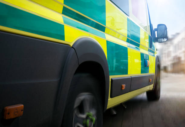 Paramedic wearing gloves is sitting with a digital tablet while transporting a patient in an ambulance