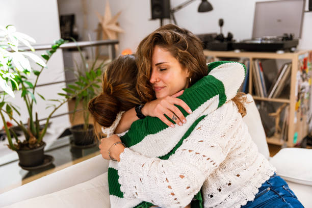 istock Medium Shot of Two Best Female Friends Hugging on Sofa 2175549401