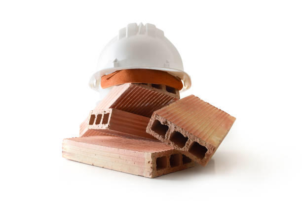 Pile of bricks and white construction helmet on top on white base isolated on white background. Front view.