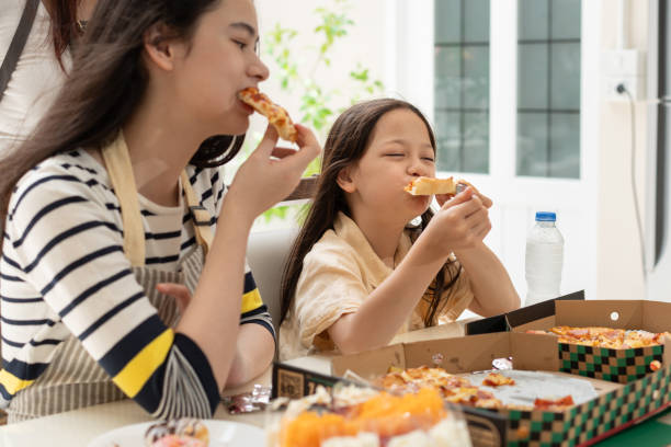 istock Happy sibling with mother eating pizza in kitchen at home 2175556111
