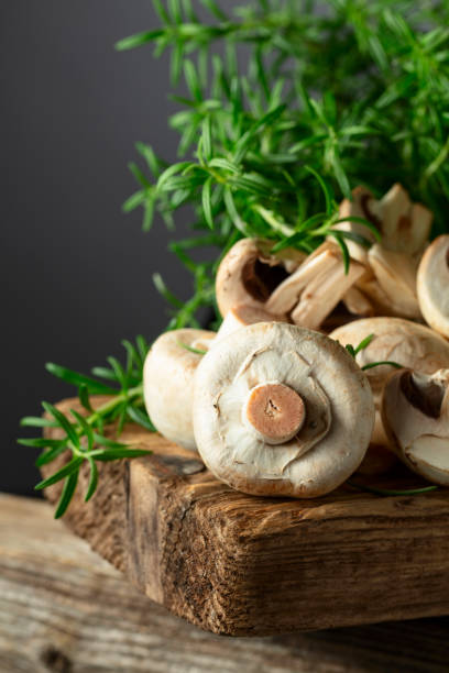 istock White champignons with rosemary on a wooden board. 2175556905