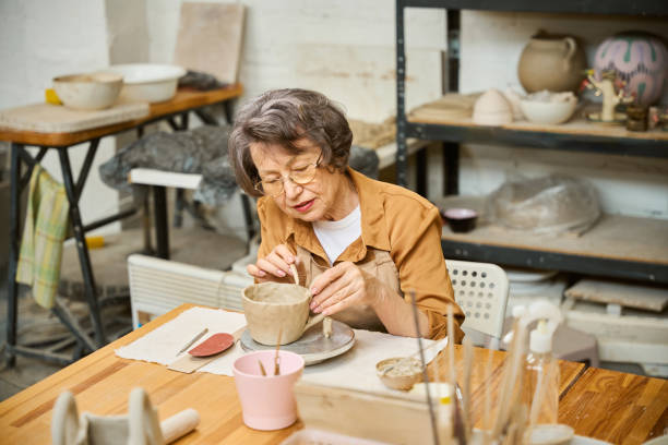 istock Elderly lady works on a clay bowl in ceramics studio 2175557603