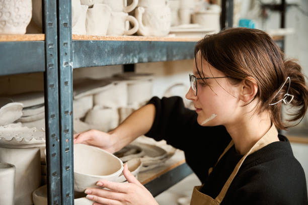 istock Young potter carefully places clay piece on rack 2175557638