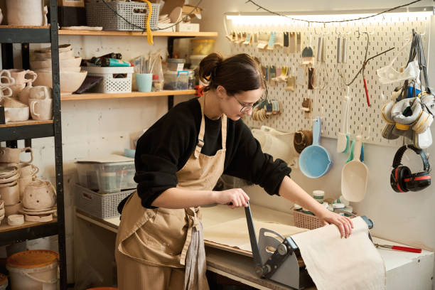 istock Female potter rolls out a layer of clay on a special machine 2175557658