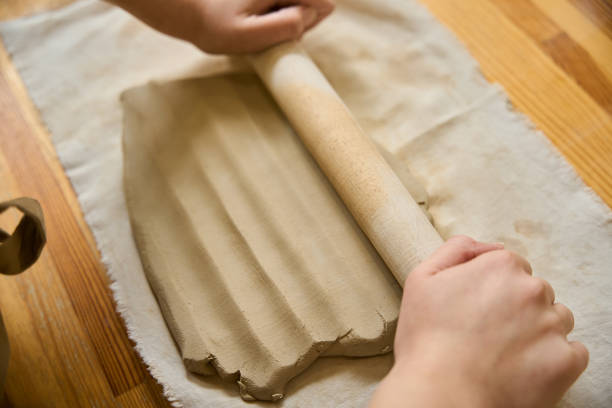istock Master rolls out a layer of clay with a wooden rolling pin 2175557659