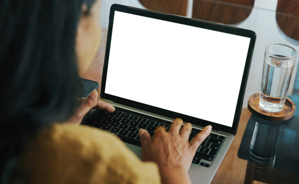 Woman Working on Laptop at Desk with Blank White Screen stock photo