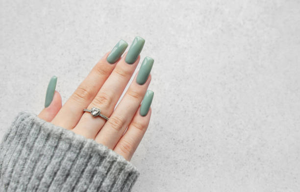 istock Elegant long green nails adorned with a delicate ring on a cozy sweater-clad hand against a soft, light background 2175560031