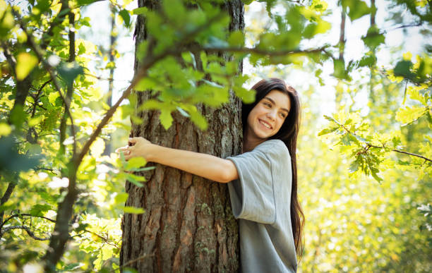 istock Young woman embracing a tree while enjoying nature in a sunlit forest during summer 2175560038