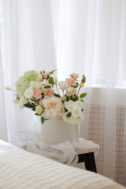 istock A white vase with pink flowers sits on a wooden stool 2175561207