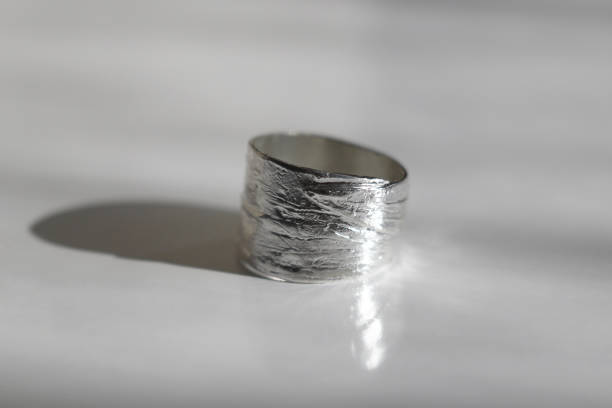 Wide textured silver ring with leaves pattern on a white background. Handmade jewelry.