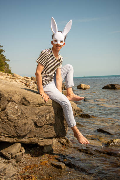 istock A young attractive guy is resting on the sea wearing a hare mask. 2175570561
