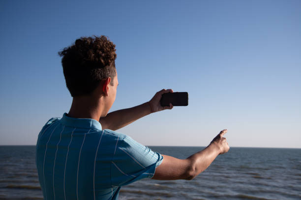 istock A young attractive guy is walking on the beach. 2175571044