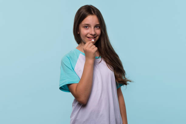 istock Girl smiles while holding white pill near mouth 2175573634