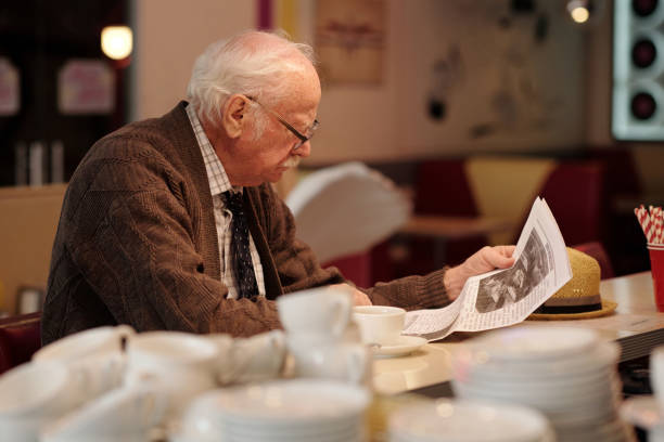 istock Elderly Man Reading Newspaper in Cozy Cafe 2175576181