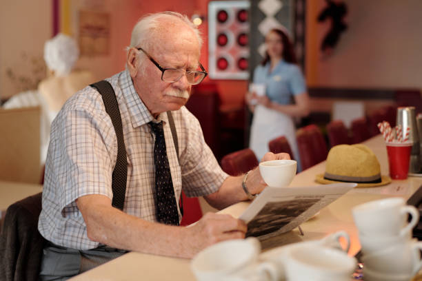 istock Elderly Man Reading Newspaper While Holding Cup of Coffee 2175576190