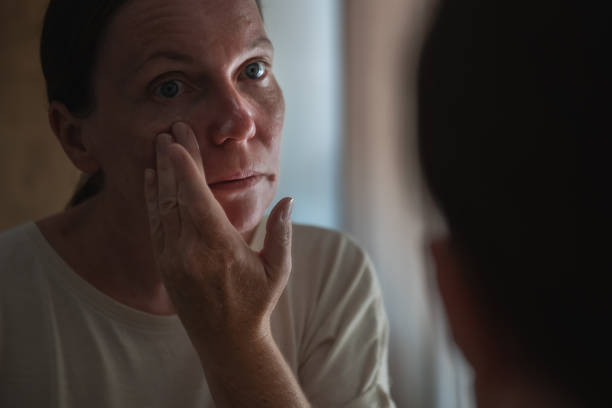 istock Woman applying facial cream while looking at mirror 2175577979