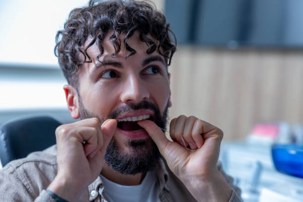 istock Bearded man carefully flossing his teeth and braces doing hygienic morning routine 2175578746