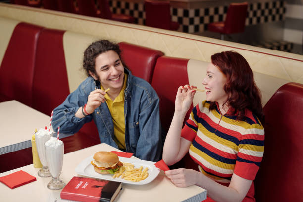 istock Smiling Friends Eating Snacks in Retro Diner Booth 2175579285