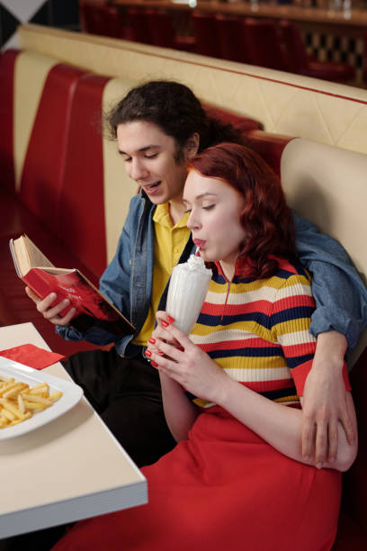 istock Sharing Milkshake and Reading Book in Retro Diner Booth 2175579288