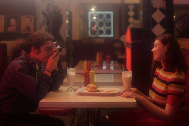 Young attractive woman drinks a delicious milkshake, inside classic vintage american retro bar. Serious woman waits, sitting at bar.