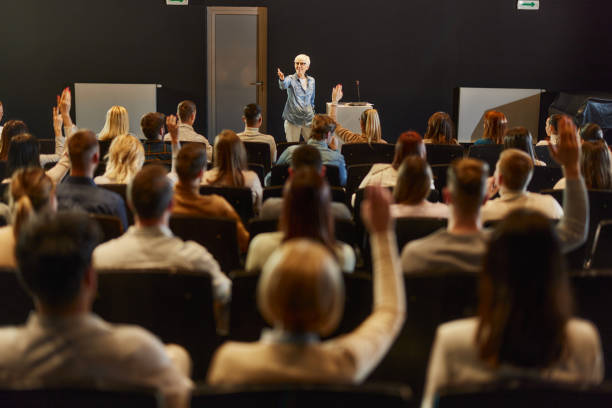 Engaging seminar at convention center! Happy mature speaker giving a speech in front of people at convention center while some of them wants to ask a question. press conference stock pictures, royalty-free photos & images