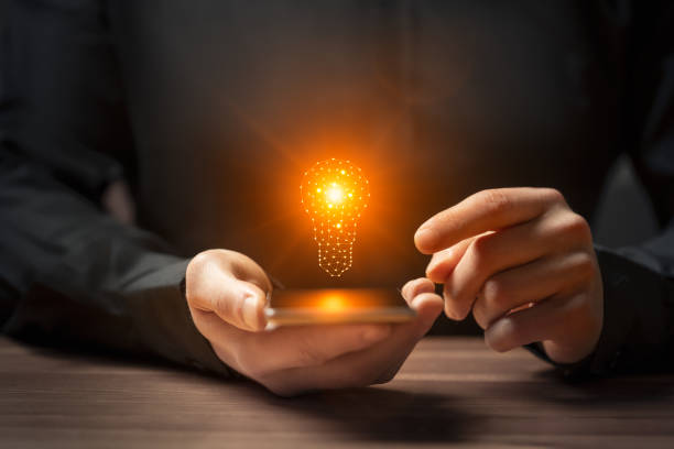 istock Idea concept with hand holding smartphone with glowing light bulb 2175581835